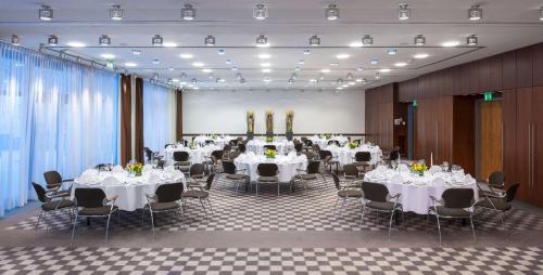 a banquet hall with white tables and chairs at Dorint An der Kongresshalle Augsburg in Augsburg