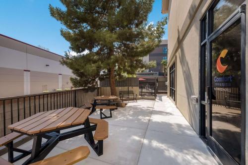 a patio with picnic tables and a tree on the side of a building at Comfort Inn & Suites Las Vegas - Nellis in Las Vegas