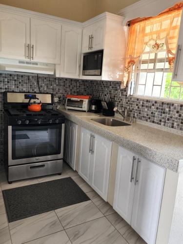 a kitchen with white cabinets and a sink and a stove at Brighton View in Bridgetown