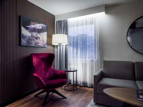 a living room with a red chair and a couch at Radisson Blu Royal Viking Hotel, Stockholm in Stockholm
