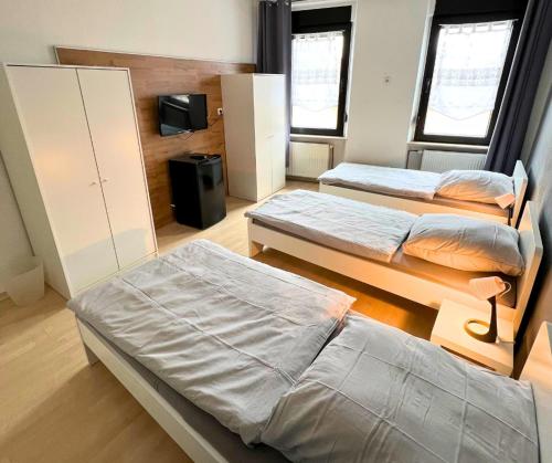 Cette chambre comprend 3 lits et une télévision. dans l'établissement 4RENT Apartments, à Worms