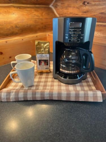 a coffee maker and two cups on a table at John's Cabin in Somers