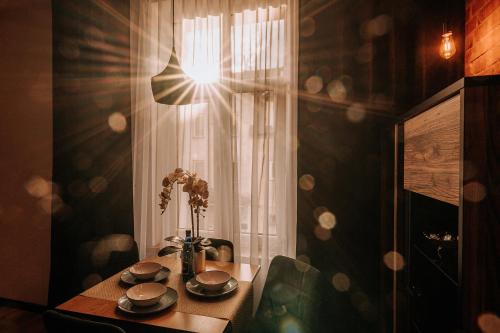 stół z wazonem kwiatów i oknem w obiekcie Apartament Mazury Kętrzyn „Kopernik” w mieście Kętrzyn