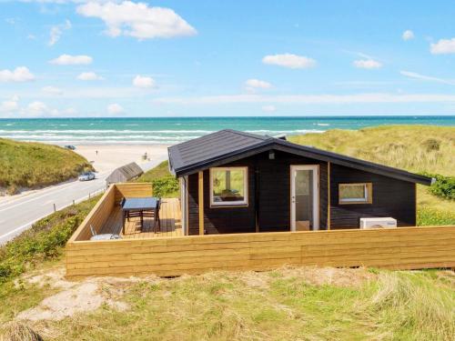 een huis op een strand met de oceaan op de achtergrond bij 4 person holiday home in L kken in Løkken