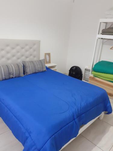 a bed in a room with a blue bedspread at Ayres Apart in Chivilcoy