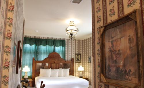 a bedroom with a bed with a painting on the wall at Copper Queen Hotel in Bisbee