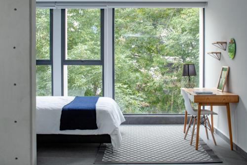 a bedroom with a bed and a desk and a large window at NIU Modern & Centric Lofts in Mexico City