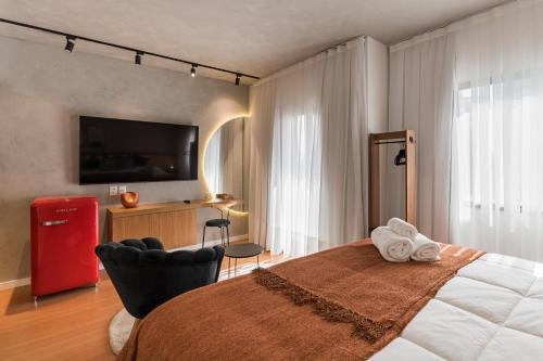 a bedroom with a bed with a television and a chair at Cyclinn Jesuíno Arruda Itaim in São Paulo