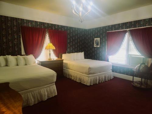 a hotel room with two beds and red curtains at Copper Queen Hotel in Bisbee