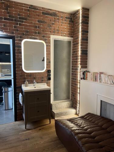 La salle de bains est pourvue d'un lavabo et d'un mur en briques. dans l'établissement Design appartment in the marais, à Paris