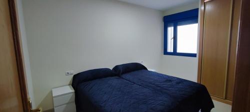 ペニスコラにあるApartamentos Peñiscola Argualasのベッドルーム1室(青い毛布付きのベッド1台付)
