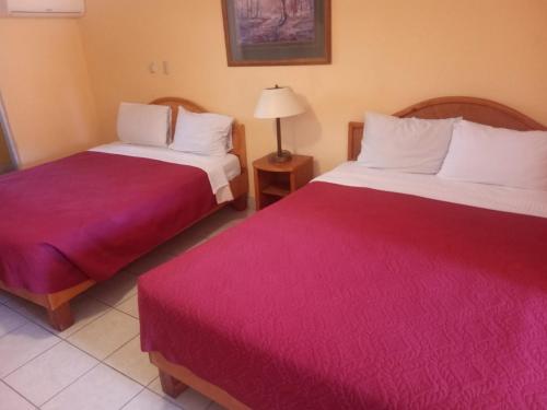 Habitación de hotel con 2 camas con sábanas rojas en HOTEL SEVILLA en Tijuana