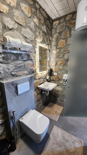 a stone bathroom with a toilet and a sink at RUSTICO in Shirokë