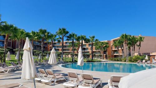 - une piscine avec des chaises longues et des parasols dans l'établissement Apartamentos Herdade dos Salgados - Vila das Lagoas, à Albufeira