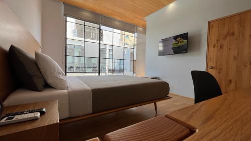 a bedroom with a bed and a desk and a window at Hotel Brecha in Tijuana