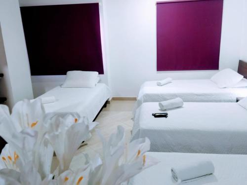 a room with two beds with white sheets and a plant at Hotel La Casa 1 in Montería