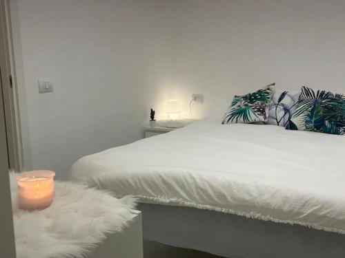 a bedroom with a white bed with a candle on a table at Pash apartment in Pero