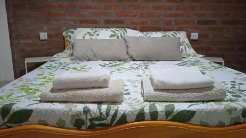 a bed with three pillows on top of it at Cabaña Rayen in Esquel