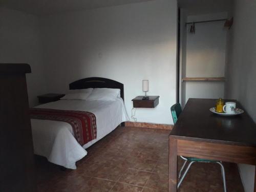 Un dormitorio con una cama y una mesa con un plato. en La Farola Cajamarca, en Cajamarca