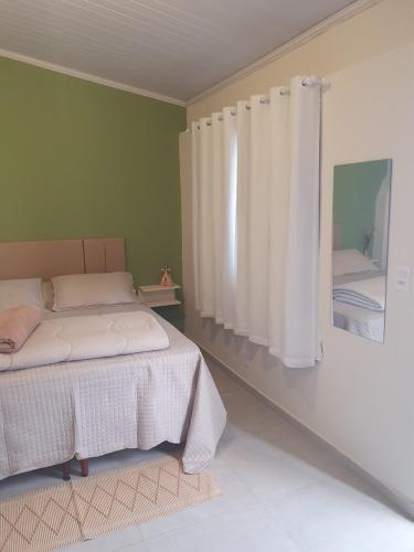 Schlafzimmer mit einem Bett und einem Fenster mit Vorhängen in der Unterkunft Suíte privativa confortável in Diamantina