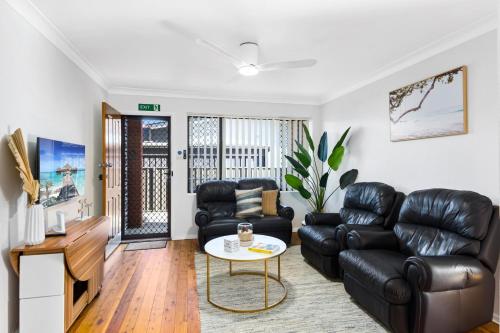 a living room with black leather furniture and a table at Pepe's Beach Pad in Towradgi