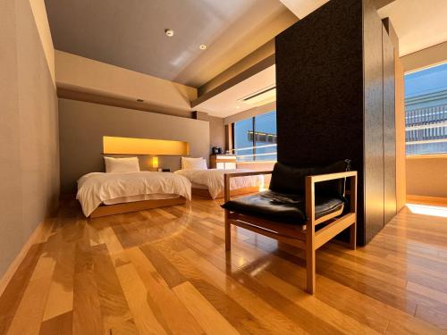 a bedroom with two beds and a chair and a window at ITSUKUSHIMA IROHA in Miyajima