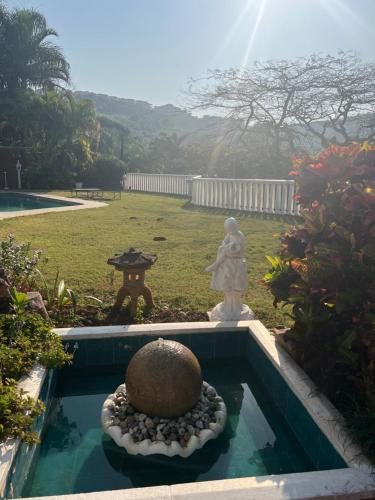 un jardin avec une statue en pierre et une fontaine dans l'établissement Villa Le Rosa Unit 3, à Durban