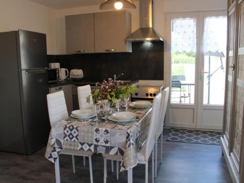 une cuisine avec une table avec des chaises et un réfrigérateur dans l'établissement Charmante maison de plain-pied avec cour privée, proche de Verteuil-sur-Charente, WiFi, plancha, parking - FR-1-653-106, à Verteuil-sur-Charente