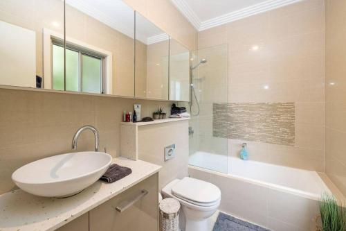 uma casa de banho com um lavatório, um WC e um chuveiro em Treetop coastal getaway in Avalon Beach em Avalon