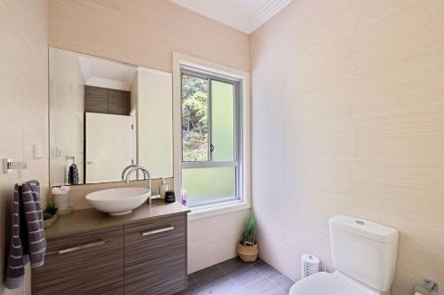 a bathroom with a sink and a toilet and a window at Treetop coastal getaway in Avalon Beach in Avalon