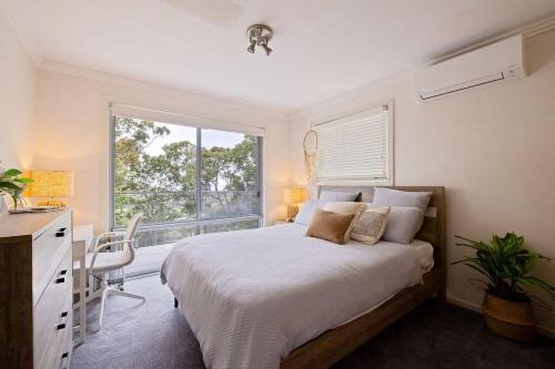 um quarto com uma cama, uma janela e uma secretária em Treetop coastal getaway in Avalon Beach em Avalon