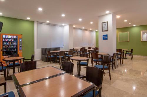 un restaurante con mesas, sillas y paredes verdes en One Coatzacoalcos Forum, en Coatzacoalcos