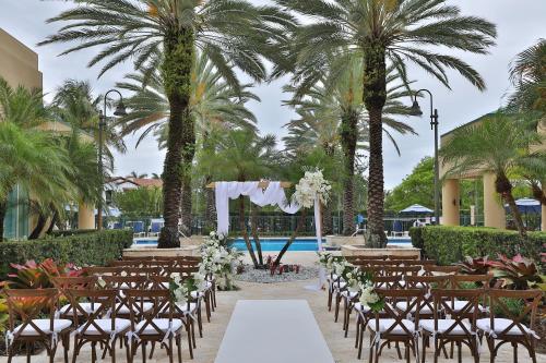 a wedding ceremony in front of a pool with palm trees at InterContinental At Doral Miami by IHG in Miami