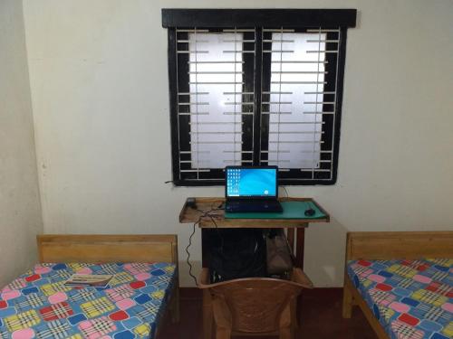 a room with two beds and a laptop computer on a desk at Rismin's Home Stay in Divulpitiya