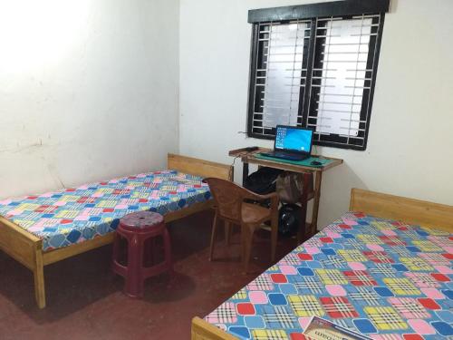 a room with two beds and a laptop on a desk at Rismin's Home Stay in Divulpitiya