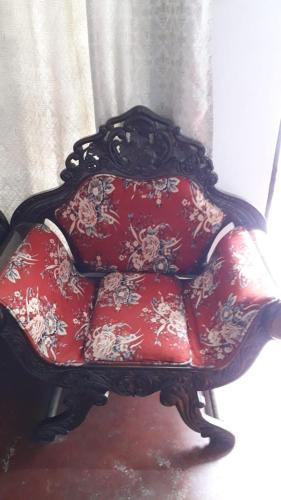 a chair with red cushions with flowers on it at Rismin's Home Stay in Divulpitiya