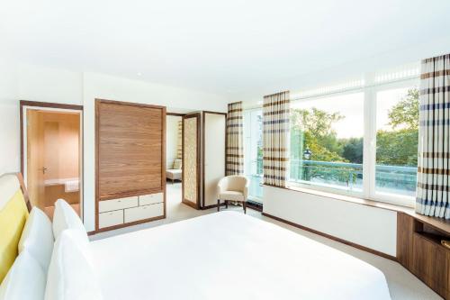 a bedroom with a bed and a desk and windows at COMO Metropolitan London in London