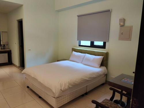 a bedroom with a bed with white sheets and a window at 站前小松鼠電梯車位民宿-豪華雙人全新升級 in Hualien City