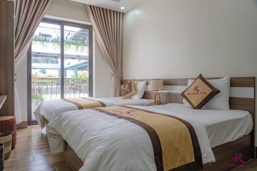2 bedden in een hotelkamer met een raam bij Roza Palace in Cat Ba