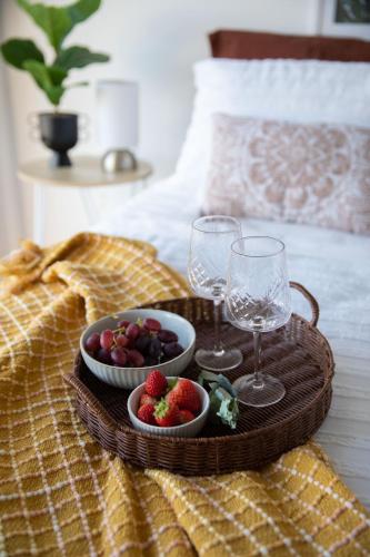 a tray with fruit and wine glasses on a bed at Nature & Relax House, Panoramic sea view, Free parking 37 in Hobart