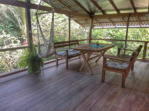 eine Veranda mit einer Hängematte sowie einem Tisch und Stühlen in der Unterkunft Mizu Spa & Hospedagem in Alter do Chao
