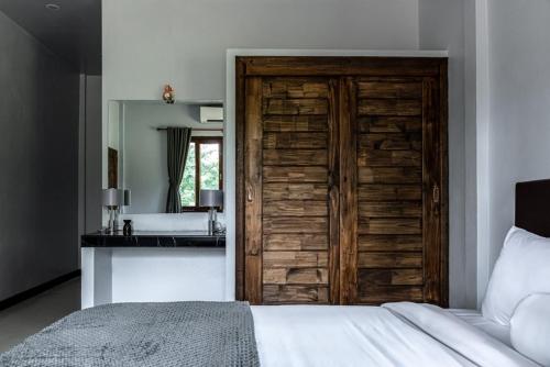 a bedroom with a wooden door and a bathroom at Anahata Resort in Lipa Noi