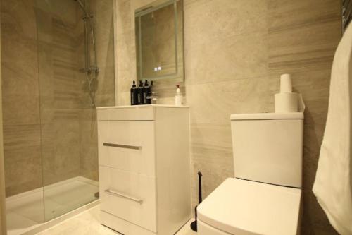 biała łazienka z toaletą i prysznicem w obiekcie 1 bedroom beachfront apartment w mieście Monkwearmouth