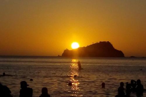 people standing on the beach watching the sunset at Espectacular Apartamento-Loft, en el Rodadero. in Gaira
