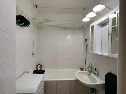 Baño blanco con bañera y lavamanos en Atomcity Apartman, en Paks