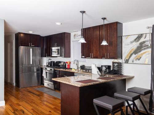 a kitchen with wooden cabinets and stainless steel appliances at Stylish & family friendly 3 Bedroom - 8 mins to EWR in Elizabeth