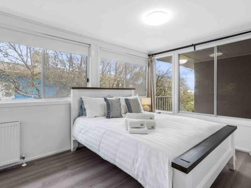1 dormitorio con 1 cama blanca grande y ventanas grandes en Picture-Perfect Mornington Getaway, en Mornington