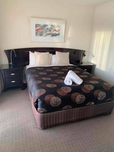 a bedroom with a large bed with two towels on it at Port Campbell Parkview Motel & Apartments in Port Campbell