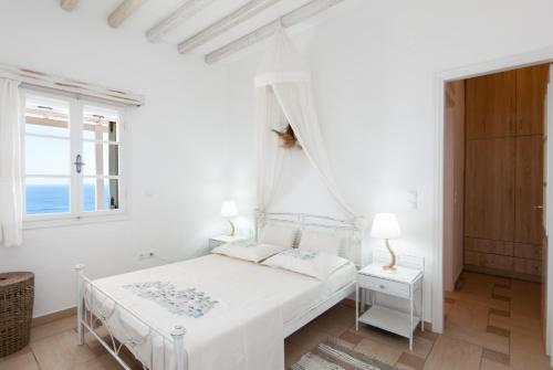 ein weißes Schlafzimmer mit einem Bett und einem Fenster in der Unterkunft Sunset Studio in Cherronisos