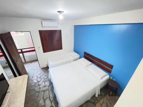um quarto com uma cama branca e uma parede azul em Pousada dos Caminhos em Aracaju